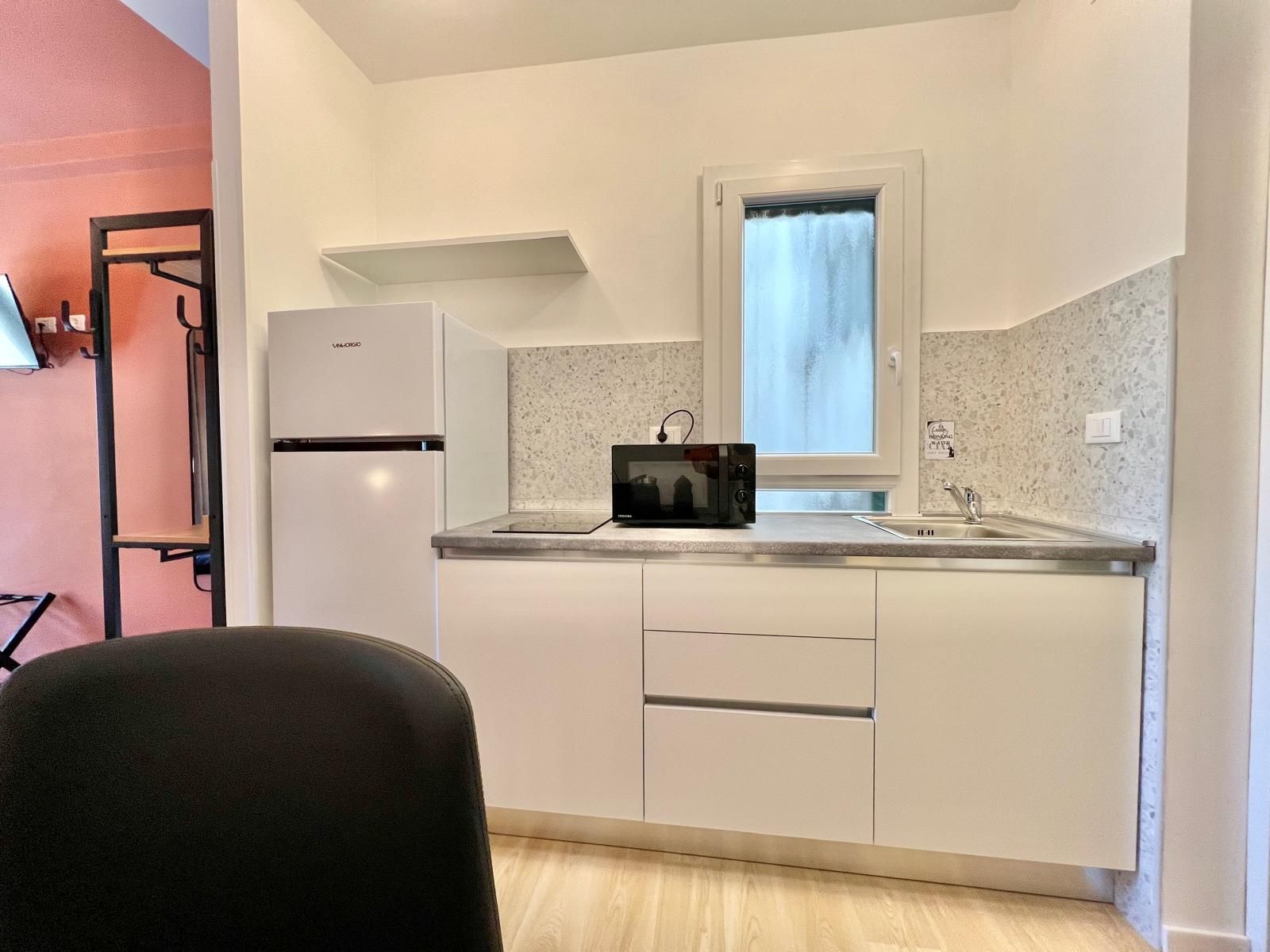 A compact kitchen with a refrigerator, microwave, and sink.