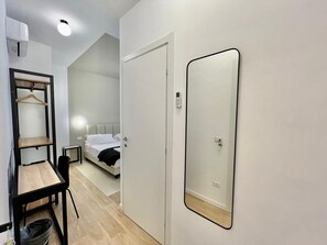 A hotel room with a bed, a bedside table, a chair, a wardrobe, a mirror, and a hanging wardrobe with shelves. - Luciano Queen's Guest House (Rome)