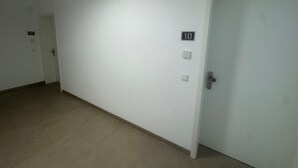 A corridor with a closed door marked with the number 10, a light switch, and a doorbell.