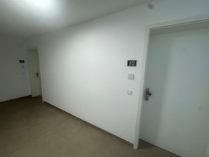 Pasillo con una puerta cerrada marcada con el número 10, un interruptor de luz y un timbre.