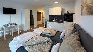 Um espaço compacto com cozinha compacta, área de refeições e cama com muitos travesseiros.