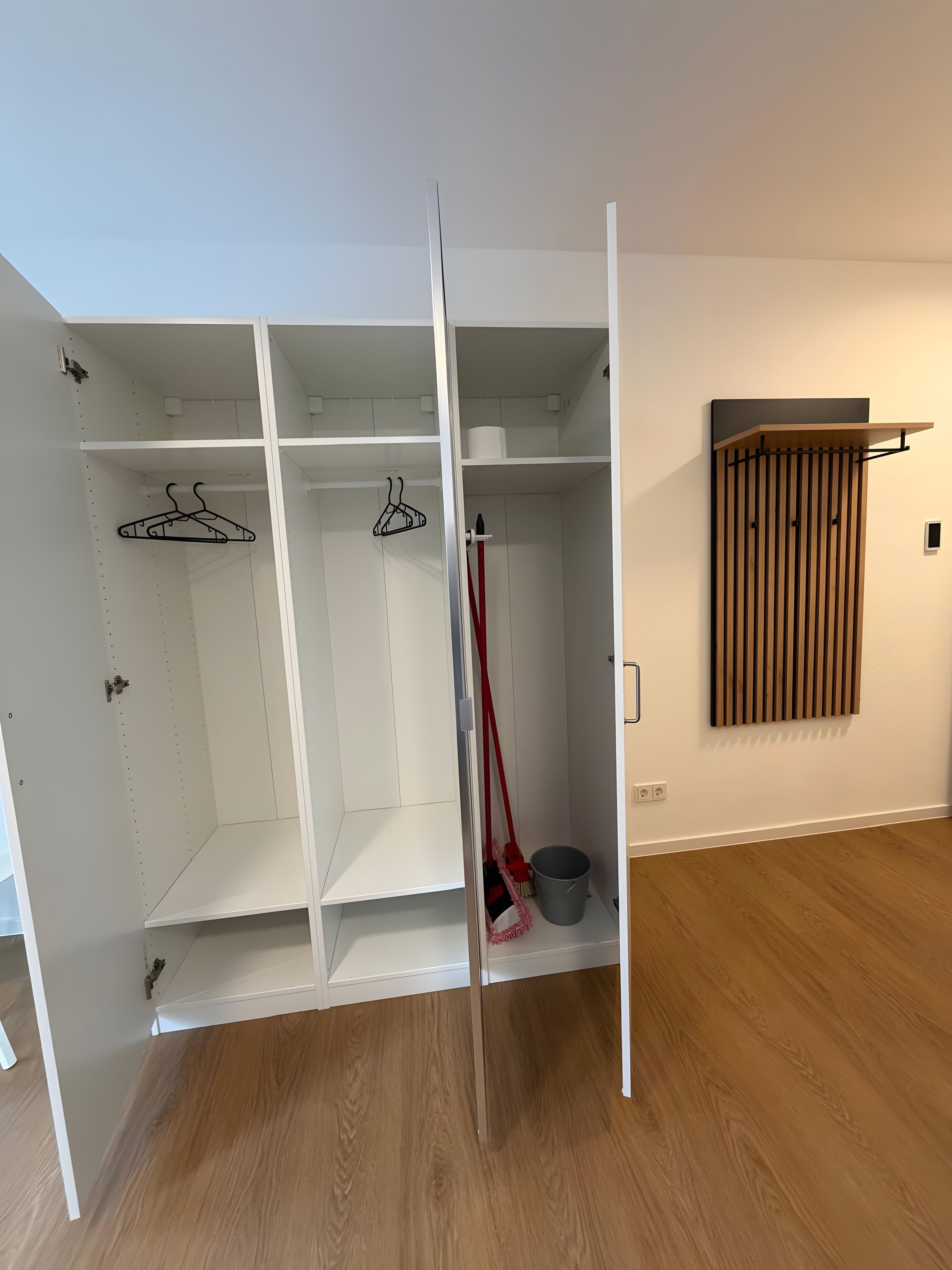 Ein begehbarer Kleiderschrank mit offenen Regalen, einer Kleiderstange und einem Heizkörper.