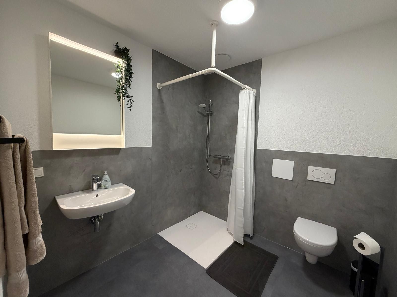 Ein modernes Badezimmer mit Dusche, Toilette und Waschbecken.