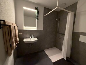 Ein modernes Badezimmer mit Waschbecken, Spiegel, Dusche und Handtuchhalter.