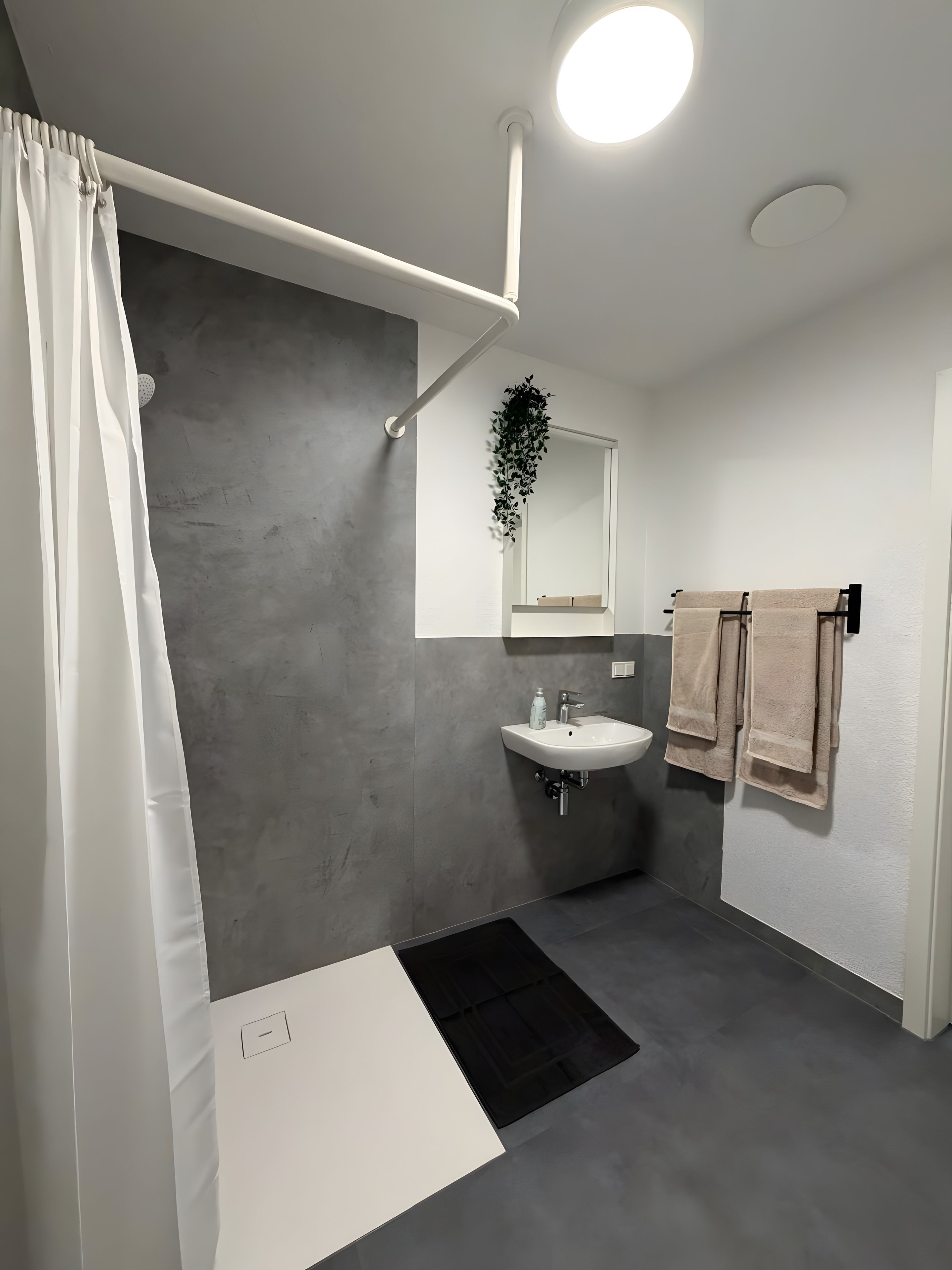 Ein modernes Badezimmer mit Dusche, Waschbecken und Handtuchhalter.