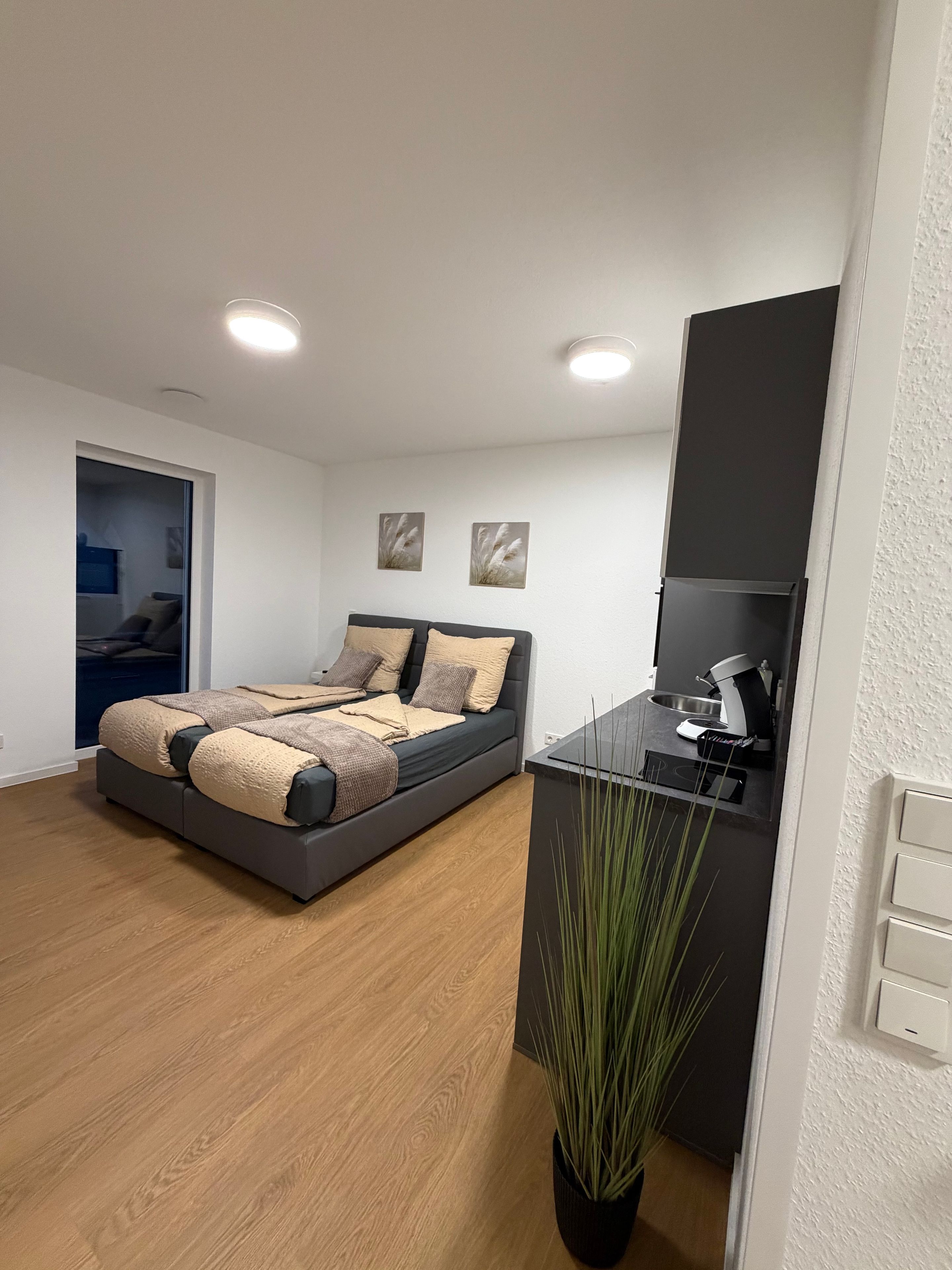 Ein modernes Schlafzimmer mit einem Bett, einem Nachttisch und einer Topfpflanze.