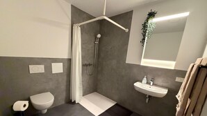 A modern bathroom with a shower, toilet, and sink. - Apartment in A Hotel 'Werner Apartments Mecklar 11' with Shared Terrace, Shared Garden and Wi-Fi (Ludwigsau)