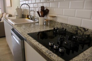 Una cocina con encimera de granito, electrodomésticos de acero inoxidable y salpicadero de azulejos blancos.
