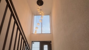 A staircase with a black railing leading to a landing with a door and a window.