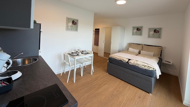 Quarto de hotel compacto com cozinha compacta, área de refeições, cama e guarda-roupa.