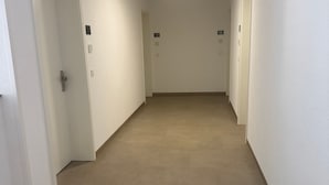 A hallway with white walls, beige carpet, and doors numbered 12 and 16.