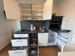 Una cocina compacta equipada con lavavajillas, cafetera y microondas.