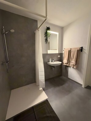 Ein modernes Badezimmer mit Dusche, Waschbecken und Handtuchhalter.