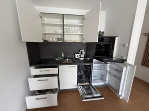 Una cocina compacta con lavavajillas integrado, cafetera y microondas.