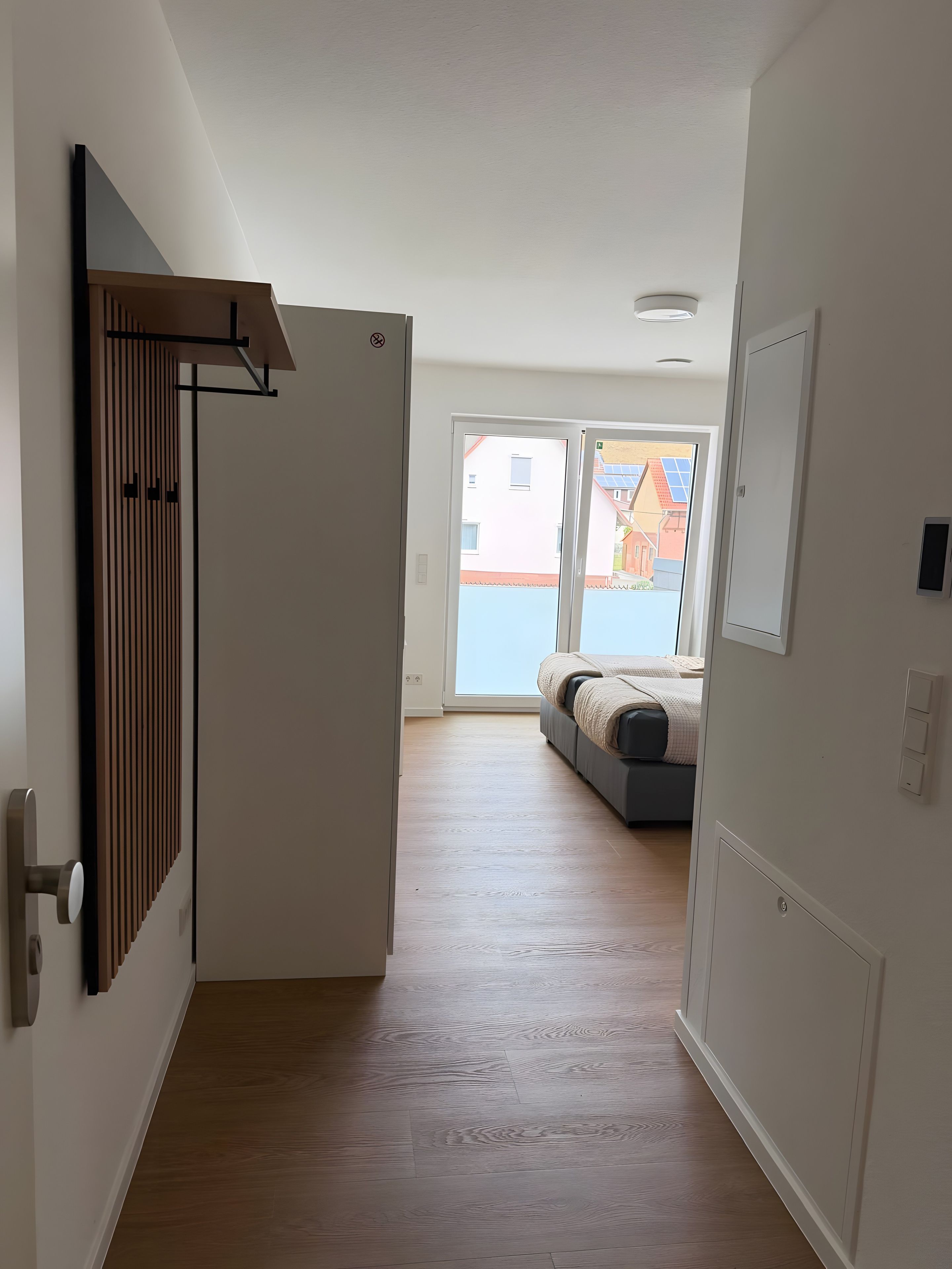 Un corridoio con una porta che dà su una stanza con un letto e vista sugli edifici esterni.