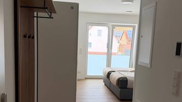 Un corridoio con una porta che dà su una stanza con un letto e vista sugli edifici esterni.