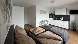 Um quarto moderno com uma cama, uma mesinha de cabeceira e um criado-mudo.