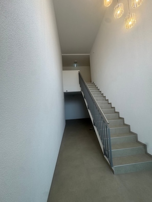 A staircase with a metal handrail and carpeted steps leading to a landing with a light fixture. - Apartment in A Hotel 'Werner Mecklar 14' with Shared Terrace, Shared Garden and Wi-Fi (Ludwigsau)
