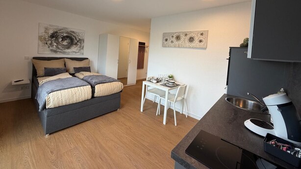Quarto moderno com cama, mesa de cabeceira e um pequeno espaço de refeições com mesa e cadeiras.