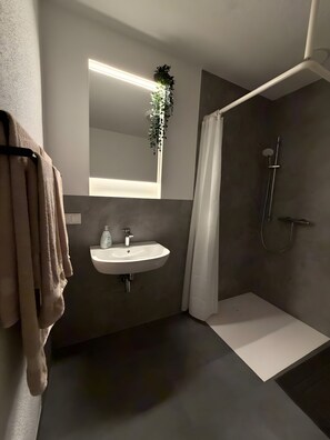 Ein modernes Badezimmer mit Waschbecken, Spiegel und Dusche.