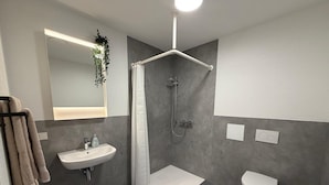A modern bathroom with a shower, toilet, and sink. - Apartment in A Hotel 'Werner Apartments Mecklar 9' with Shared Terrace, Shared Garden and Wi-Fi (Ludwigsau)
