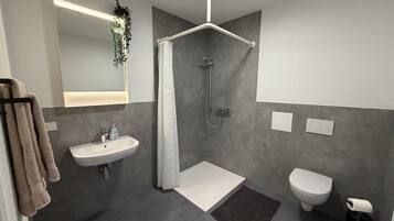 Un bagno moderno con doccia, wc e lavandino.
