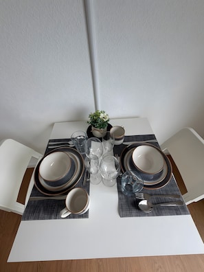 A dining table set with plates, bowls, glasses, and a small potted plant. - Apartment in A Hotel 'Werner Apartments Mecklar 13' with Shared Terrace, Shared Garden and Wi-Fi (Ludwigsau)