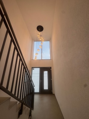 Eine Treppe mit schwarzer Geländer führt zu einer Zwischenebene mit einer Tür und einem Fenster.