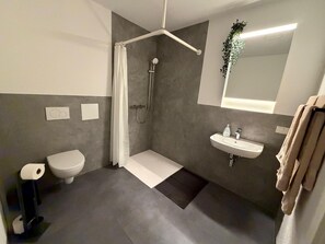 A modern bathroom with a shower, toilet, and sink. - Apartment in A Hotel 'Werner Apartments Mecklar 13' with Shared Terrace, Shared Garden and Wi-Fi (Ludwigsau)
