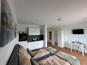 A modern bedroom with a large bed, a kitchenette, a dining area, and a TV mounted on the wall. - Apartment in A Hotel 'Werner Apartments Mecklar 13' with Shared Terrace, Shared Garden and Wi-Fi (Ludwigsau)