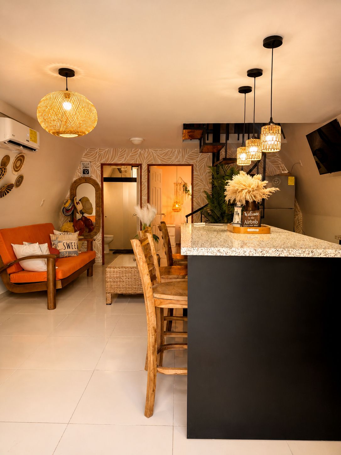 Een moderne keuken met een centraal eiland, hangende verlichting en een eethoek met houten stoelen.