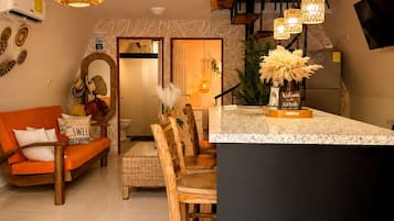 Een moderne keuken met een centraal eiland, hangende verlichting en een eethoek met houten stoelen.