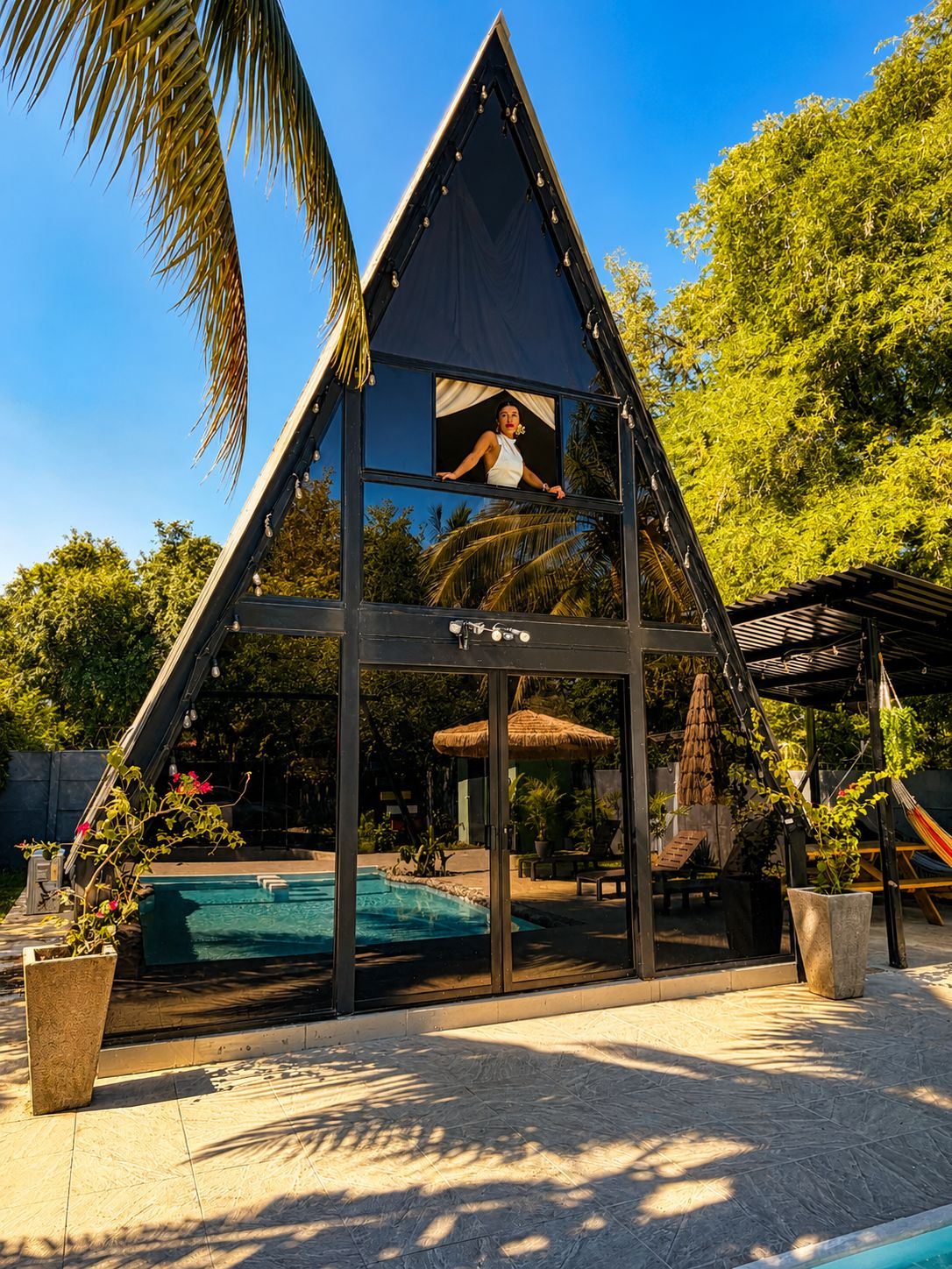 Un edificio moderno dalla forma triangolare con una piscina di fronte.