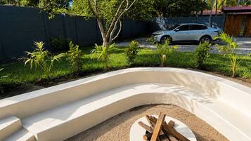 A landscaped outdoor area with a circular seating area, steps leading up to it, and a white car parked in the background.
