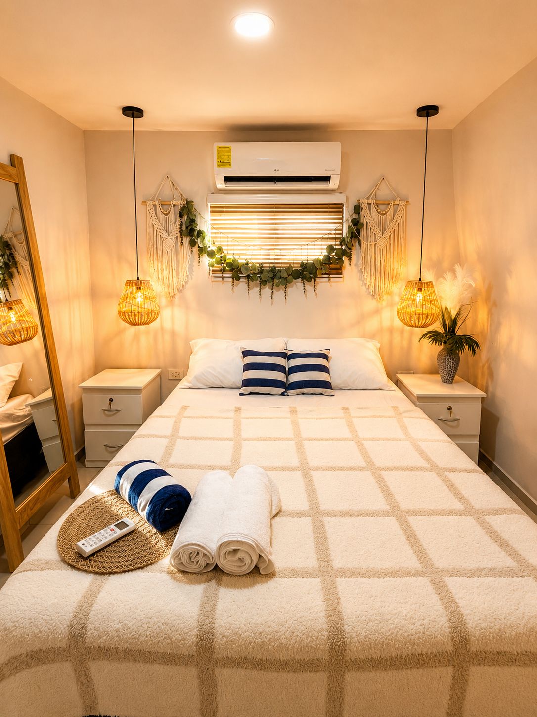Quarto bem arrumado com cama, mesas de cabeceira, um espelho e um aparelho de ar condicionado.