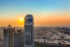 Un paisaje urbano con modernos rascacielos, cielo despejado y un atardecer.