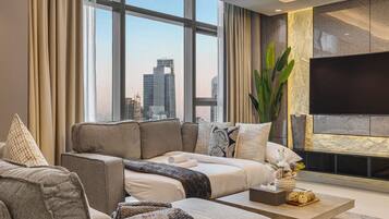 A modern living room with a large window, a flat-screen TV, and a sofa set.