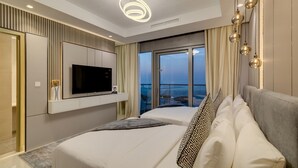 A modern hotel room with a large bed, a television, and a balcony with a city view. - Luxury Skyline 2BR with Infinity Pool (Dubai)