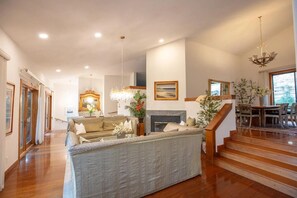 Amplia sala de estar con chimenea, una escalera y un comedor con muebles de madera.