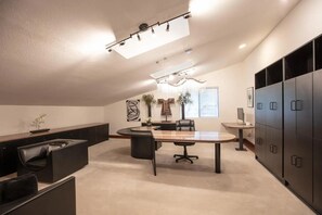 A modern office space with a curved conference table, black leather chairs, a large cabinet, and a potted plant.