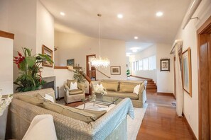 A spacious living room with a sofa set, a glass coffee table, and a chandelier.