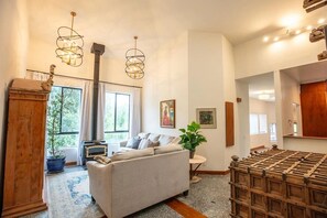A living room with a sofa, a fireplace, a large window, and a dining area with a wooden table.