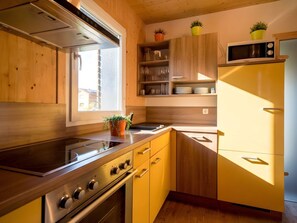 A modern kitchen with wooden cabinets, a stainless steel stove, and a built-in microwave. - Cabin With 1 Bedroom (Sankt Georgen am Kreischberg)