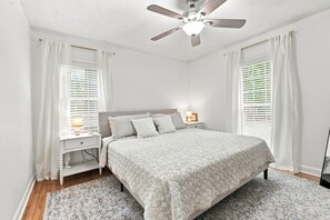 A bedroom with a bed, nightstand, lamp, and ceiling fan. - Little Minnow - 3 Bedrooms - Mainland (Pawleys Island)