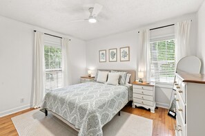 A bedroom with a bed, bedside tables, a dresser, and a ceiling fan. - Little Minnow - 3 Bedrooms - Mainland (Pawleys Island)