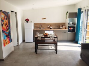 A modern kitchen with a dining table set for two, a refrigerator, and a coffee machine. - Cozy 2-bedroom house Les Epesses with AC (Les Epesses)