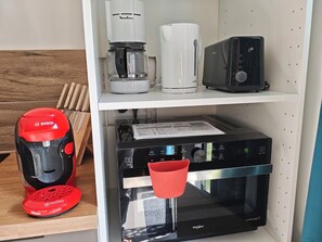 A kitchen area with a coffee maker, toaster, and microwave on the shelf, and a red coffee machine on the counter. - Cozy 2-bedroom house Les Epesses with AC (Les Epesses)