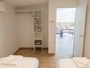 A hotel room with a wooden floor, a white wardrobe, a small kitchen area, and a bed with a neatly folded white towel. - Cozy 2-bedroom house Les Epesses with AC (Les Epesses)
