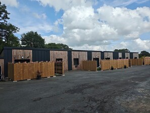 A row of wooden buildings with multiple doors, likely a commercial property with a paved parking area. - Cozy 2-bedroom house Les Epesses with AC (Les Epesses)