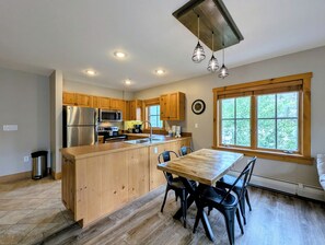 A modern kitchen with wooden cabinets, stainless steel appliances, and a large island with seating. - Prime Location | Steps to Slopes | King Bed (Keystone)